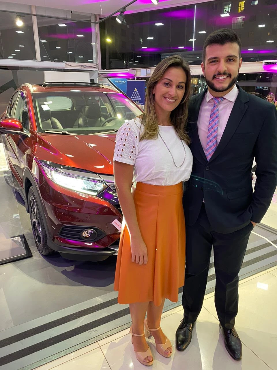 Aline Zia ao lado do apresentador Matheus Ribeiro em ambiente automotivo