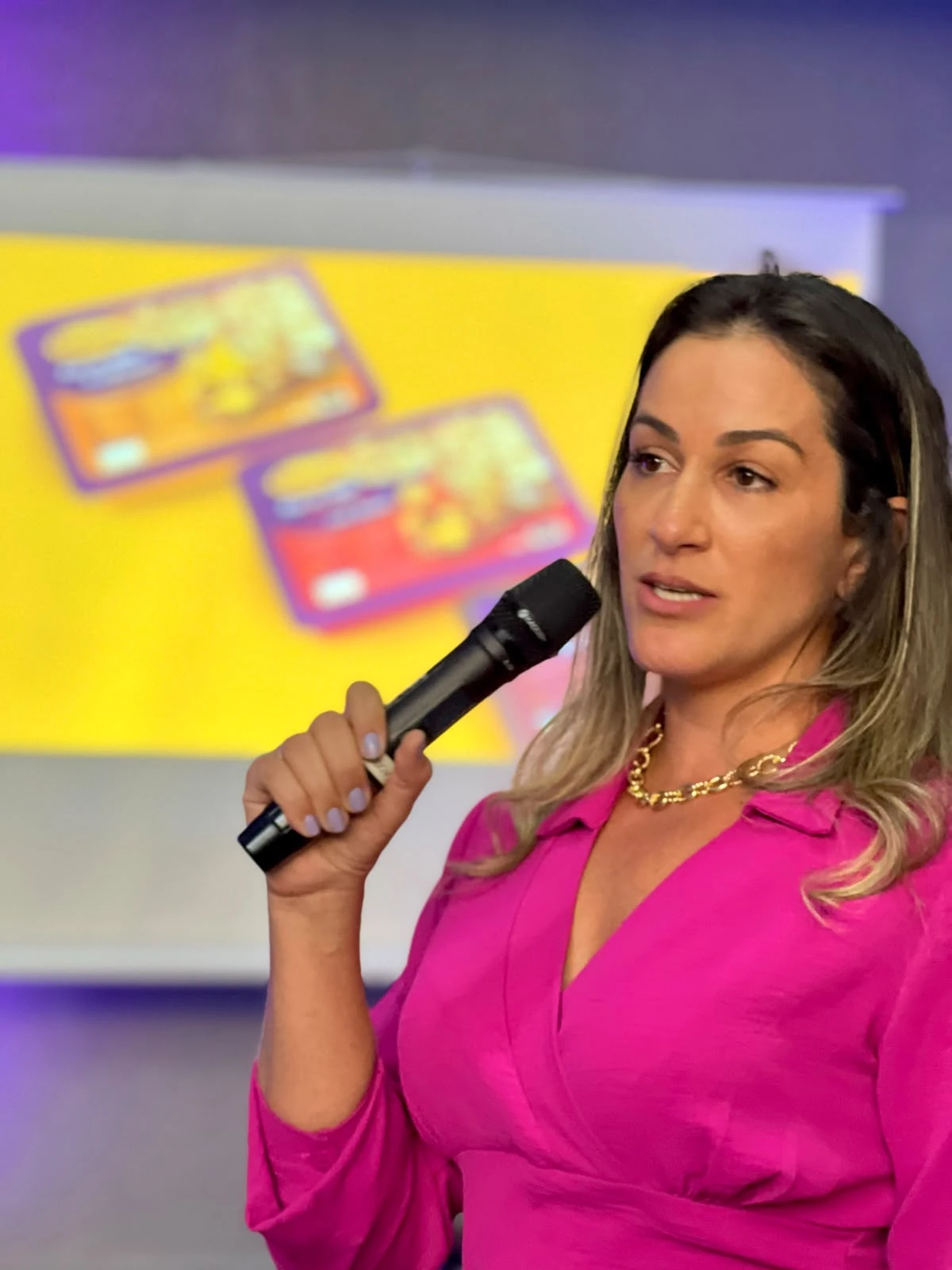 Aline Zia falando ao microfone em palestra da Cative